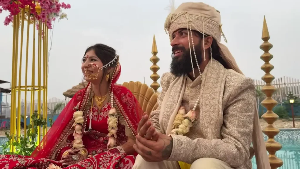 Traditional Indian wedding moment showing the bride in red lehenga and groom in cream sherwani during the ceremony.